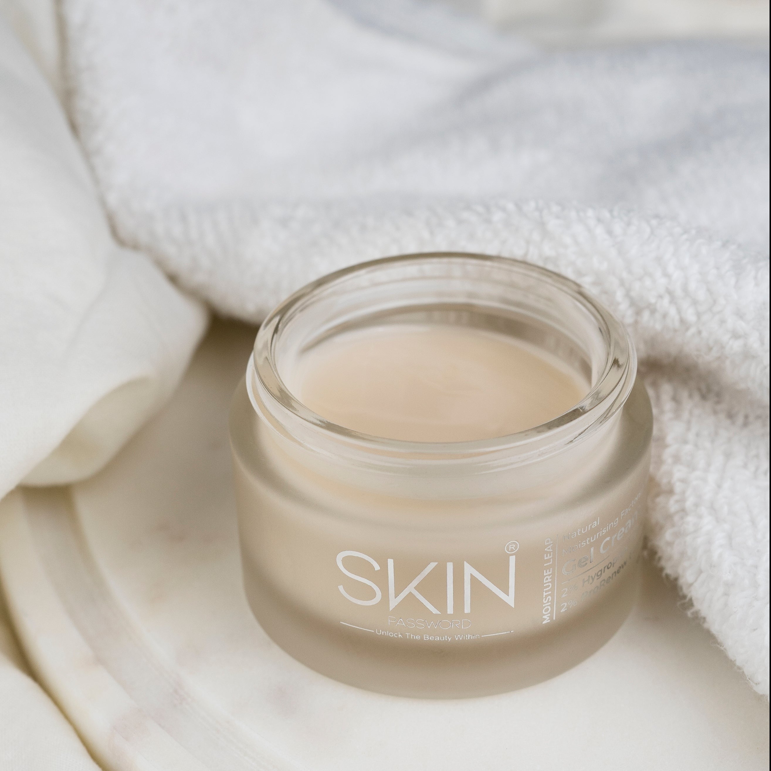 An open jar of SkinPassword MoistureLeap Gel Cream placed on cozy white fabric.